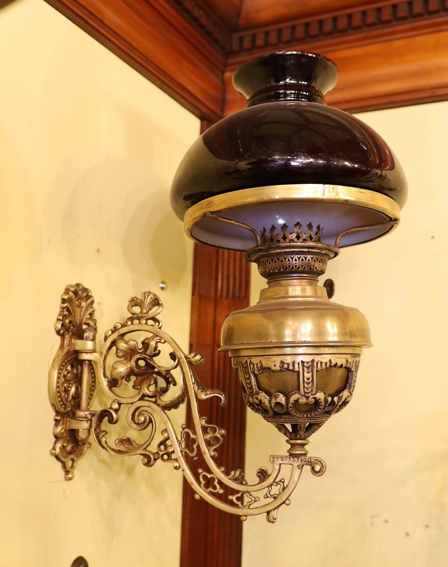 A pair of Victorian brass wall mounted oil lamps, with swivelling foliate pierced branches and aubergine glass shades, height overall 40cm